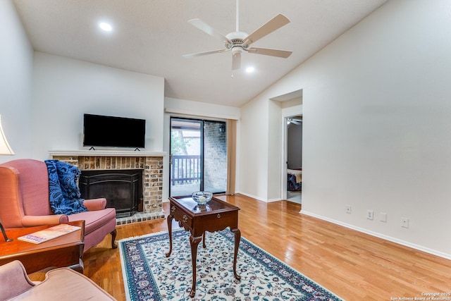 living room featuring wood finished floors, a fireplace, baseboards, ceiling fan, and vaulted ceiling
