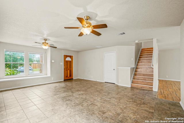 unfurnished living room featuring ceiling fan and a textured ceiling