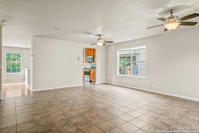 unfurnished living room with a healthy amount of sunlight, light tile patterned floors, and a textured ceiling