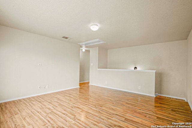 spare room with light hardwood / wood-style floors and a textured ceiling