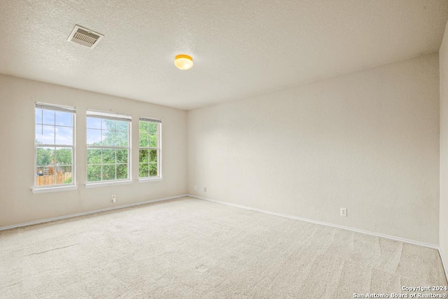 unfurnished room featuring light carpet and a textured ceiling