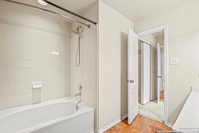 bathroom featuring tile patterned flooring, tiled shower / bath combo, a textured ceiling, and vanity