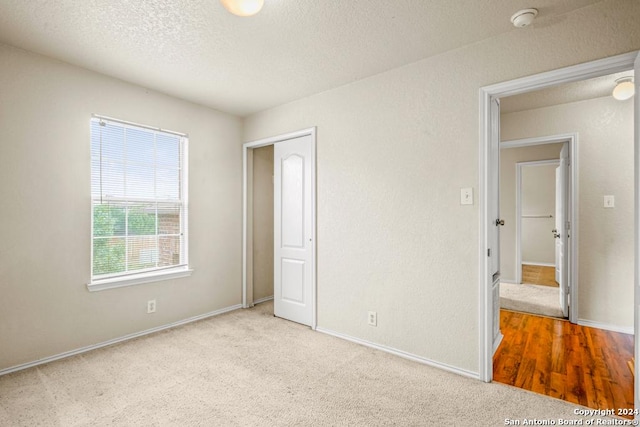 unfurnished bedroom featuring light colored carpet and a textured ceiling