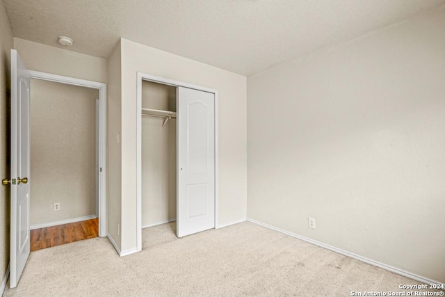 unfurnished bedroom featuring light carpet and a closet