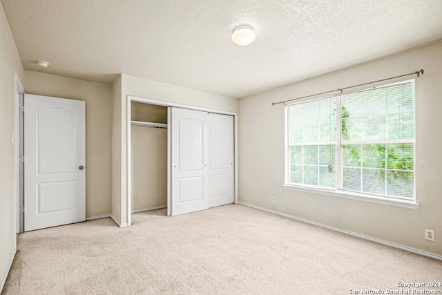 unfurnished bedroom featuring a closet, light colored carpet, and a textured ceiling