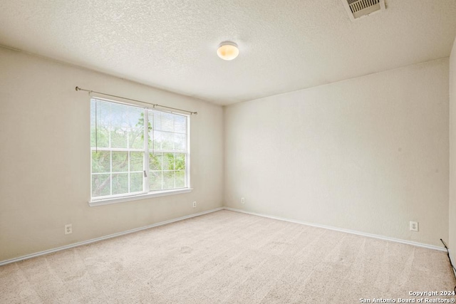 carpeted empty room featuring a textured ceiling