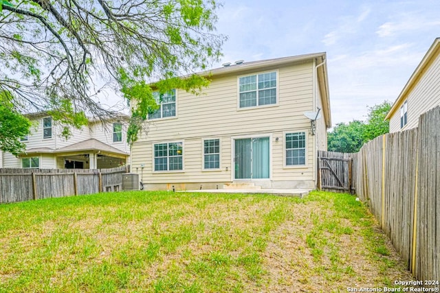 back of property with central AC unit and a yard