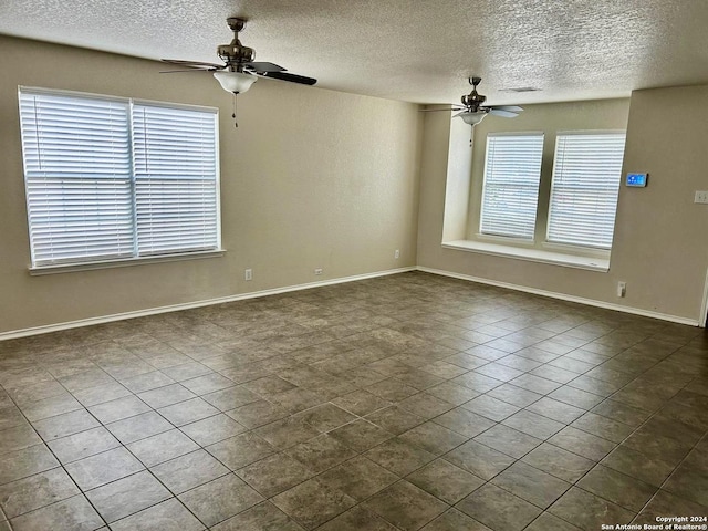 empty room featuring dark tile patterned floors, plenty of natural light, and ceiling fan