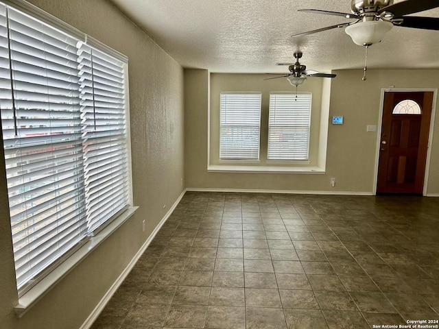 interior space featuring a textured ceiling, dark tile patterned flooring, and ceiling fan