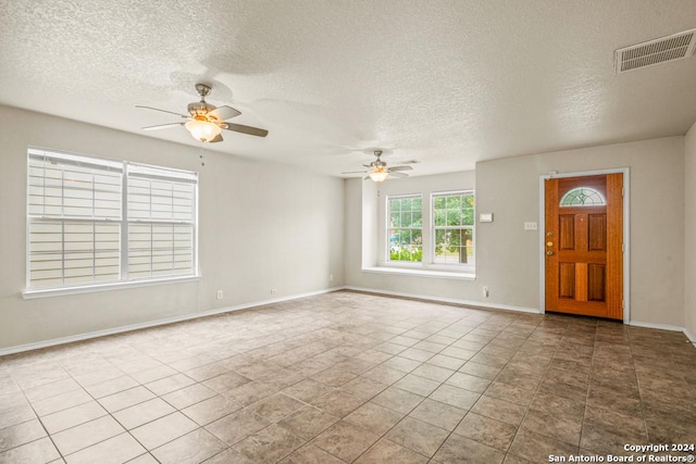 foyer with ceiling fan, light tile patterned floors, and a textured ceiling