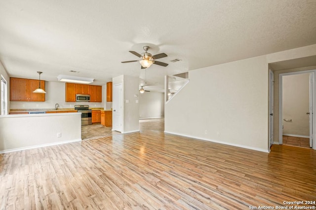 unfurnished living room with light hardwood / wood-style flooring, ceiling fan, and sink