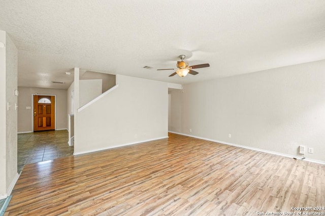 empty room featuring a textured ceiling, light hardwood / wood-style flooring, and ceiling fan