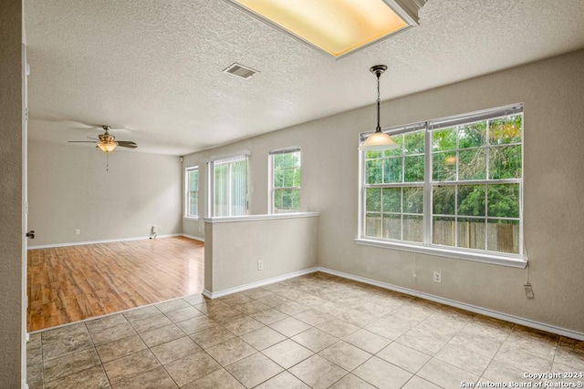 tiled empty room with ceiling fan and a textured ceiling