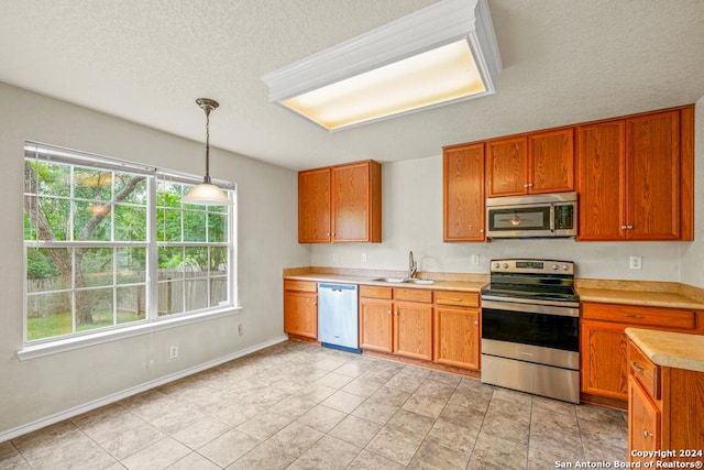 kitchen with appliances with stainless steel finishes, a textured ceiling, hanging light fixtures, and sink