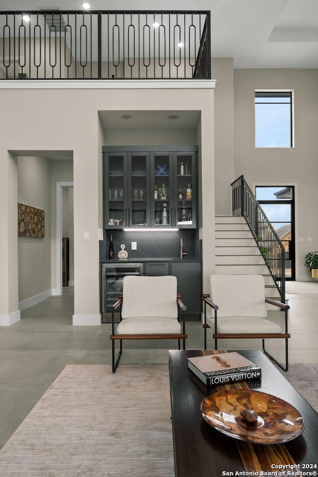 living room featuring bar area, concrete floors, and wine cooler