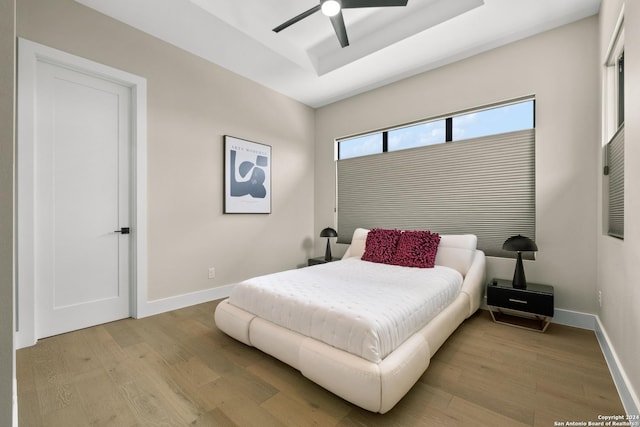 bedroom featuring a tray ceiling, ceiling fan, and light hardwood / wood-style floors