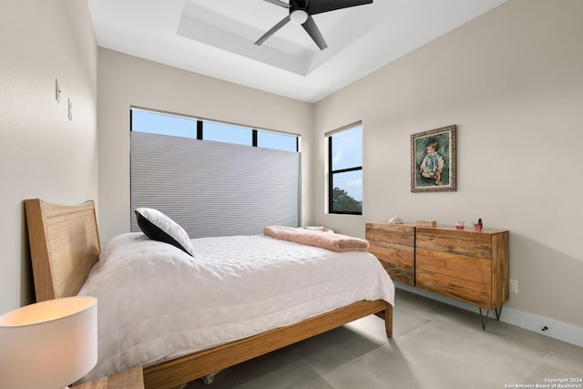 bedroom with ceiling fan and a raised ceiling