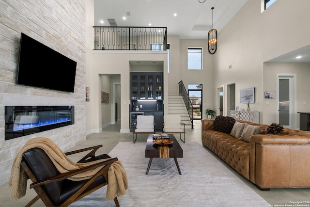 living room featuring a notable chandelier, a towering ceiling, a fireplace, and beverage cooler