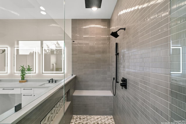 bathroom featuring tile patterned flooring, a tile shower, and vanity