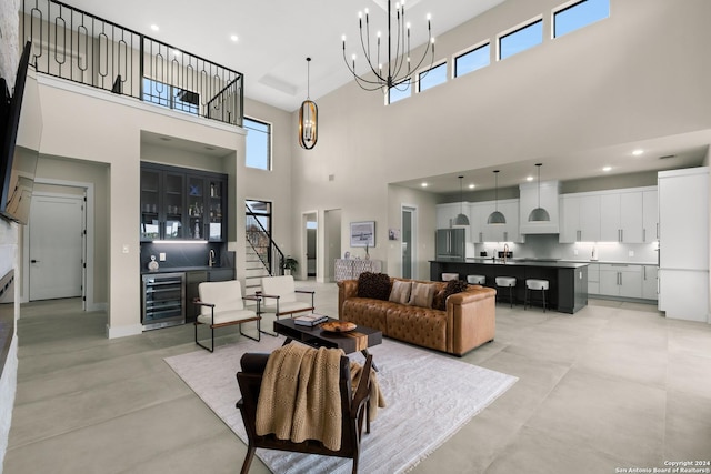 living room featuring wine cooler, plenty of natural light, a high ceiling, and an inviting chandelier