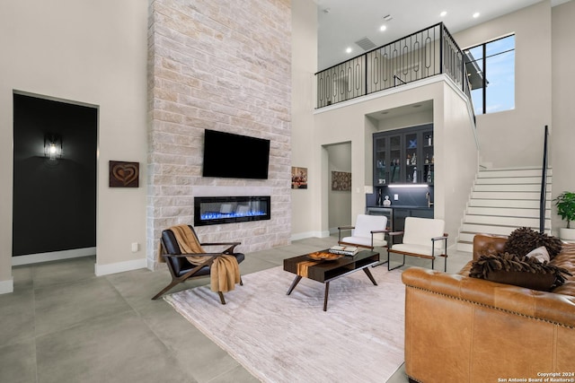 living room featuring a fireplace, a high ceiling, and bar area