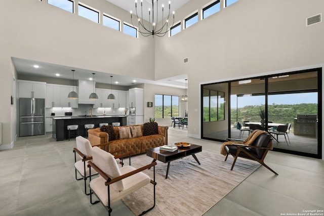 living room with sink, a high ceiling, and a chandelier