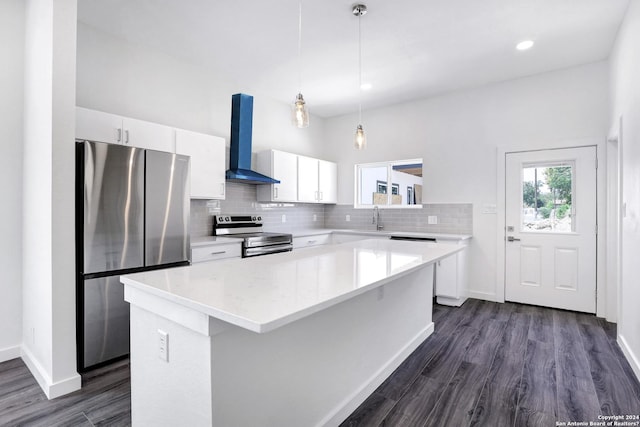 kitchen featuring white cabinetry, a center island, wall chimney exhaust hood, pendant lighting, and appliances with stainless steel finishes