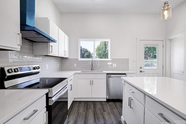 kitchen featuring wall chimney exhaust hood, white cabinetry, sink, and appliances with stainless steel finishes