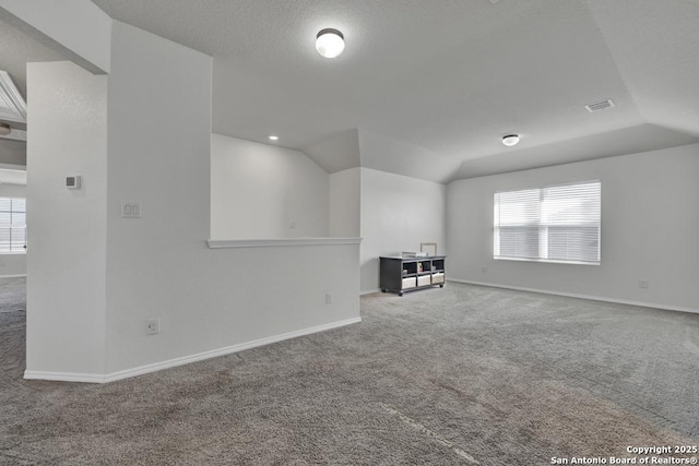 spare room featuring carpet flooring, a healthy amount of sunlight, and lofted ceiling