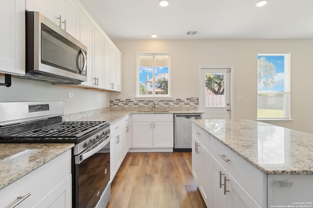 kitchen featuring white cabinetry, appliances with stainless steel finishes, sink, and light stone counters