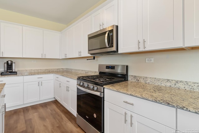 kitchen with white cabinetry, light stone counters, dark hardwood / wood-style floors, and appliances with stainless steel finishes