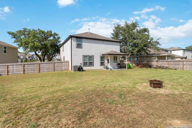 back of property featuring cooling unit, an outdoor fire pit, and a lawn