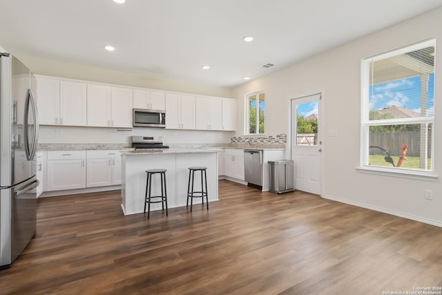 kitchen featuring a center island, appliances with stainless steel finishes, dark hardwood / wood-style floors, a kitchen breakfast bar, and white cabinets