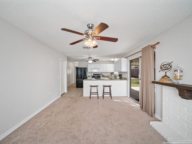 kitchen with white cabinets, black fridge, a textured ceiling, light colored carpet, and kitchen peninsula