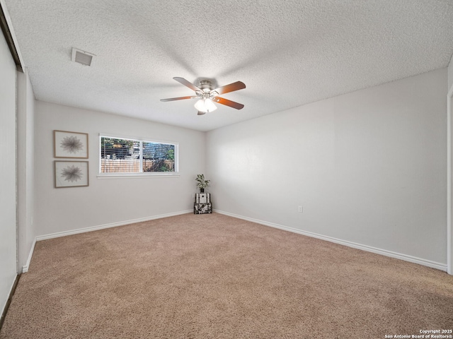 carpeted empty room with ceiling fan and a textured ceiling