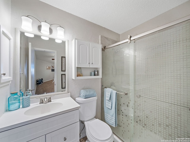 bathroom featuring vanity, toilet, a shower with door, and a textured ceiling