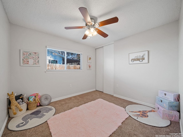 interior space featuring carpet flooring, a textured ceiling, and ceiling fan