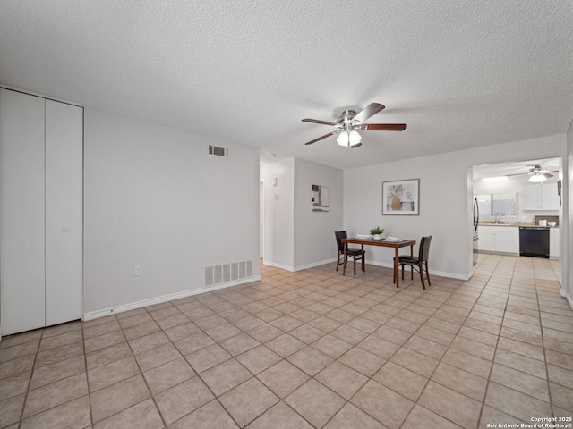 interior space with ceiling fan, sink, light tile patterned floors, and a textured ceiling