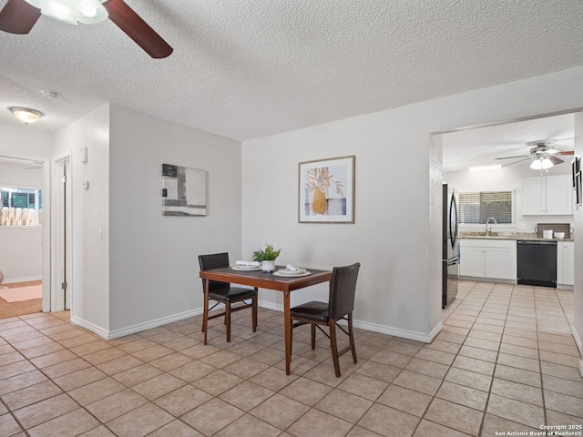 dining room featuring ceiling fan, sink, light tile patterned floors, and a textured ceiling