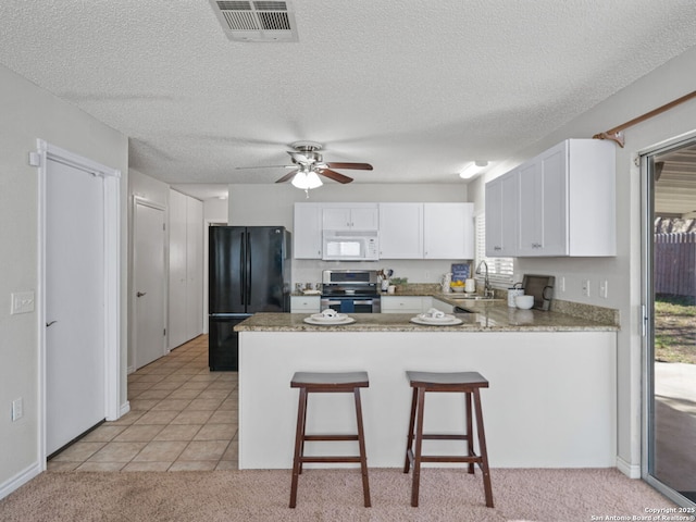 kitchen featuring sink, kitchen peninsula, stainless steel electric range, black refrigerator, and white cabinets