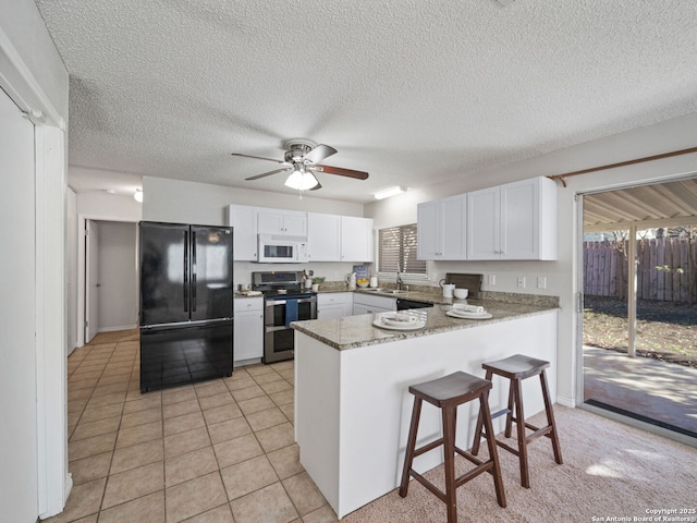 kitchen featuring kitchen peninsula, black fridge, white cabinets, and stainless steel electric range