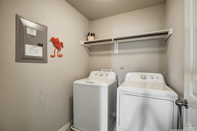 laundry area with a textured ceiling, electric panel, and washing machine and clothes dryer