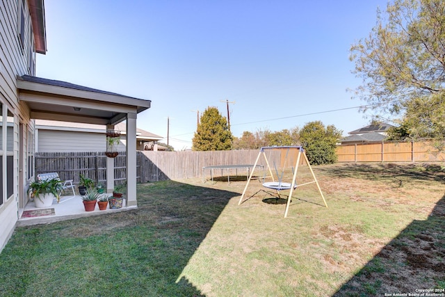 view of yard featuring a trampoline and a patio