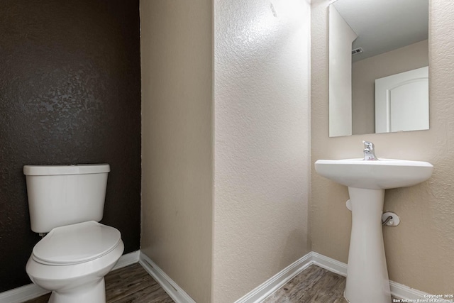 bathroom featuring wood-type flooring and toilet