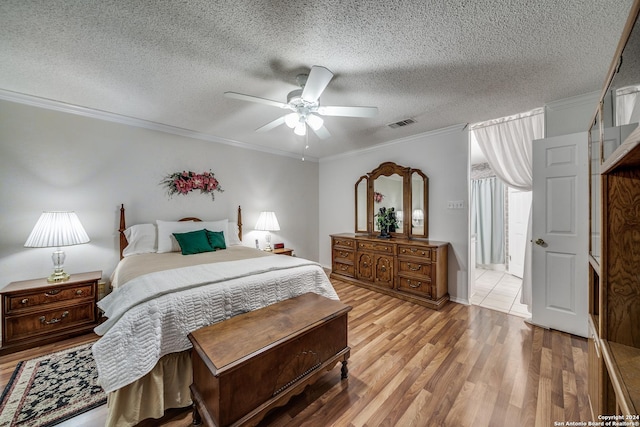 bedroom featuring a textured ceiling, light hardwood / wood-style floors, ceiling fan, and ornamental molding