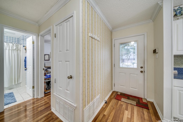 entryway with ornamental molding, a textured ceiling, and light hardwood / wood-style flooring