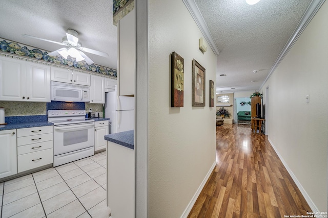 kitchen featuring white cabinets, a textured ceiling, white appliances, and backsplash