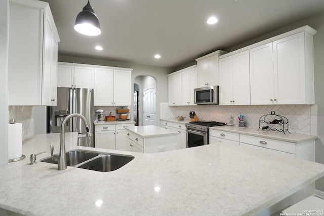 kitchen with white cabinetry, sink, stainless steel appliances, decorative light fixtures, and a kitchen island