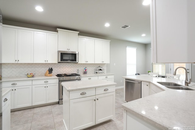 kitchen with appliances with stainless steel finishes, a center island, white cabinetry, and sink