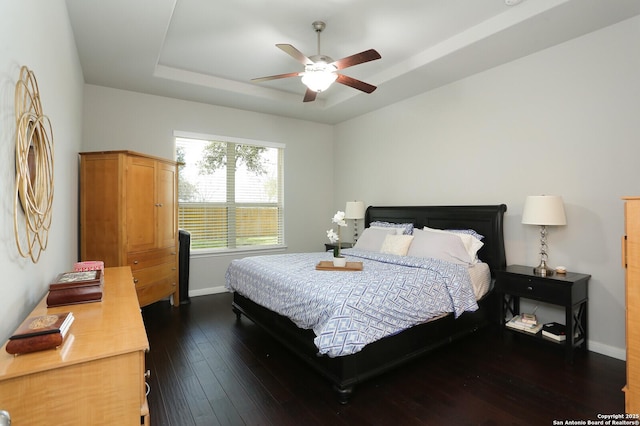 bedroom featuring a raised ceiling, ceiling fan, and dark hardwood / wood-style flooring